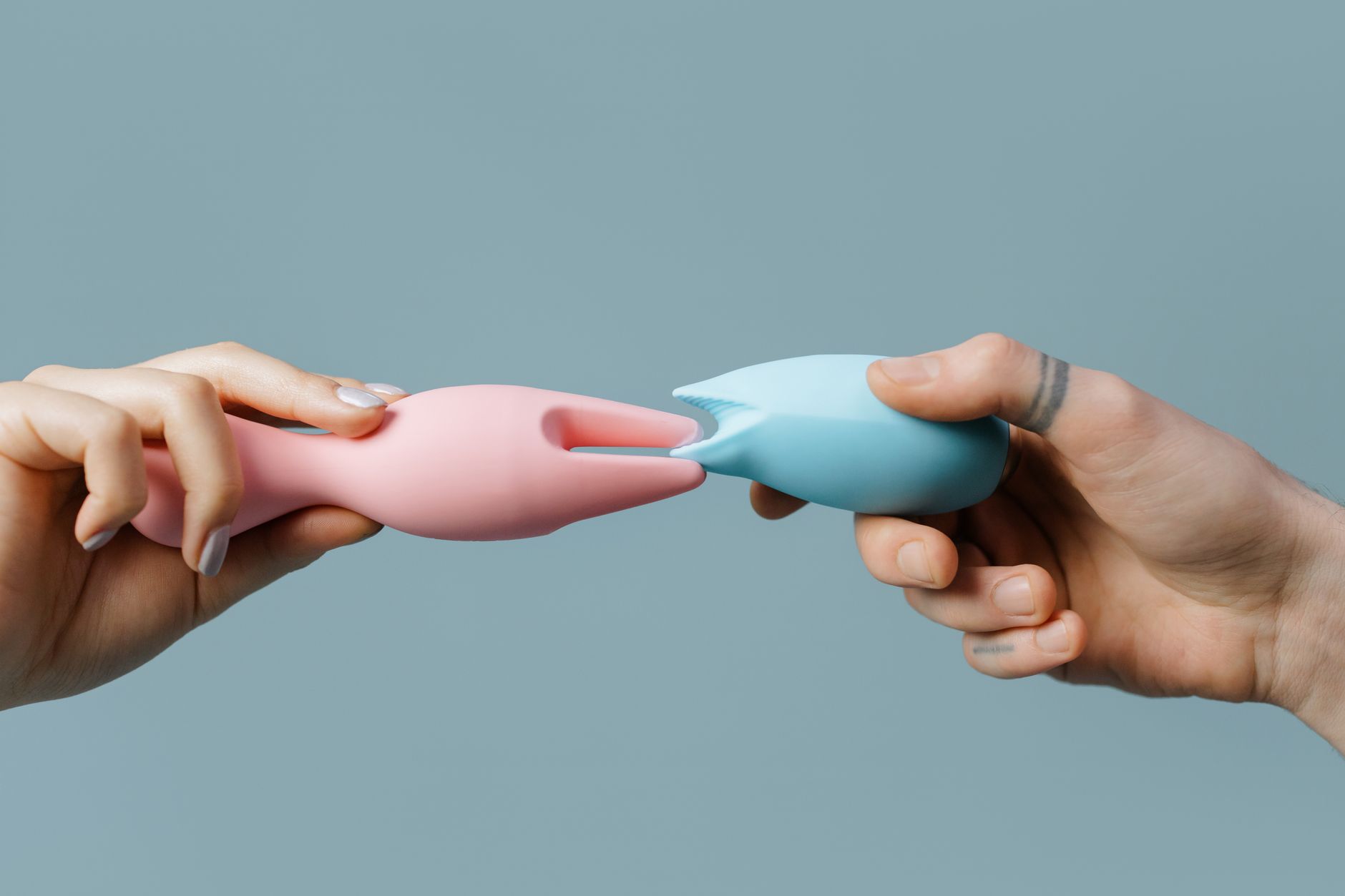 Close-up of hands holding a blue personal massager against a knitted sweater.