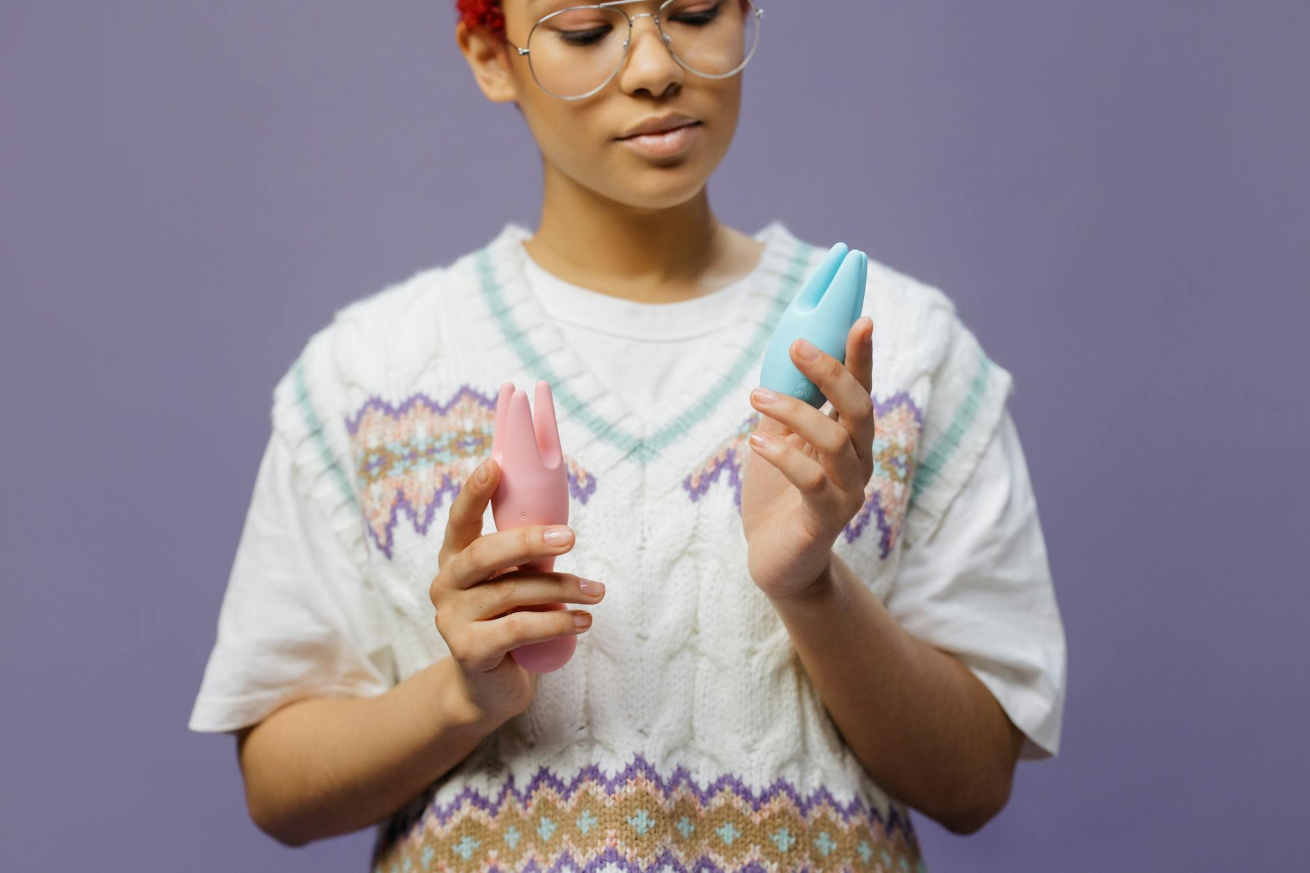Woman holding a blue and pink vibrator while thinking, representing intimate self-care during desire mismatch